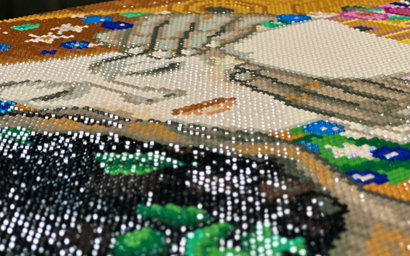 Close-up of faces in completed framing with stretcher bars of diamond painting rendering of Gustav Klimt's "The Kiss"